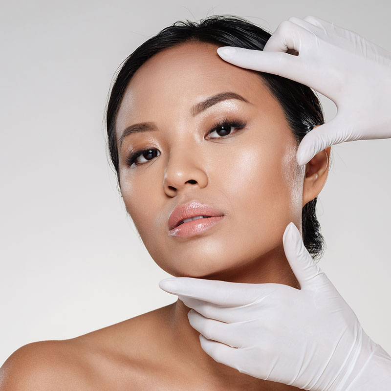 Mujer asiática con cara hermosa y sostenida por manos de cirujano plástico