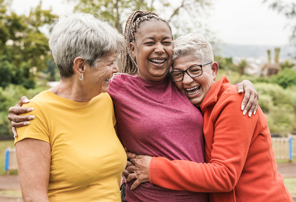Tres mujeres felices, sonríen abrazadas para vivir mejor